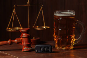Beer mug, car keys, and a gavel placed near scales of justice illustrating DUI evidence and law.