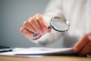 Professional examining paperwork using a magnifying glass - symbolizing scrutiny and analysis of financial agreements or legal contracts.