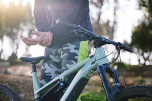 Cyclist outdoors experiencing wrist pain and injury during fitness and mountain bike training. Athlete with muscle strain and sports accident in nature.