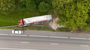 Aerial view of a commercial truck that veered off a Missouri highway crushing a guardrail and a small vehicle representing a serious truck accident injury claim in Southeast Missouri