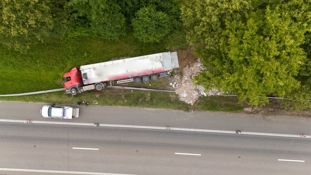 Aerial view of a commercial truck that veered off a Missouri highway crushing a guardrail and a small vehicle representing a serious truck accident injury claim in Southeast Missouri