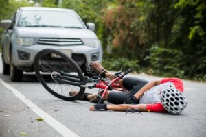 An Asian mountain biker was hit by a car on the road, resulting in injuries. 