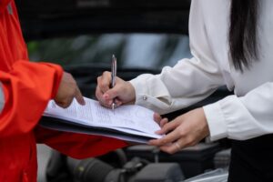 After a traffic accident, an insurance agent inspects the damaged vehicles and submits a post-accident claim report, illustrating the insurance process. 