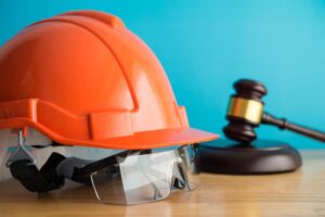 The image of a judge's gavel paired with a construction helmet and safety glasses on a wooden table symbolizes the intersection of labor law and construction safety. 