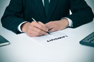 A lawyer sits in his office, holding a document labeled "Lawsuit."