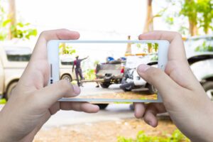 A girl is using her mobile phone, with a blurred image of a road accident in the background, highlighting the dangers of distracted driving.