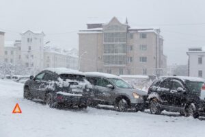 Multiple cars involved in an accident on a slippery, snow-covered city street. Hazardous road conditions during snowfall led to the crash in snowy winter weather.