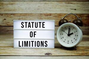 "Statute of Limitations" is displayed on an LED lightbox, accompanied by an alarm clock, all set against a rustic wooden background.