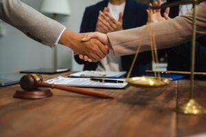 Middle-aged partner lawyers shaking hands after successfully discussing and finalizing a contract agreement.