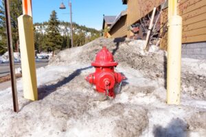 Vibrant fire hydrant partially covered in dirty snow, emphasizing the importance of keeping fire hydrants accessible during the winter months.