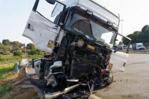 Damaged truck parked in a parking lot after being involved in an accident, with visible dents and debris.