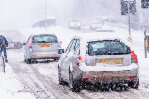 Car driving through a snowstorm with heavy snowfall and reduced visibility on the road.