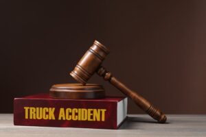 Truck accident law book and judge's gavel placed on a wooden table with a brown background.