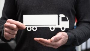 Man holding a paper cutout of a truck, symbolizing the concept of truck insurance.