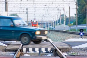 Railway crossing through which an old passenger car passes while crossing the railway tracks in front of an approaching train,