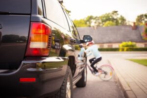 Accident. Small girl on the bicycle crosses the road in front of a car