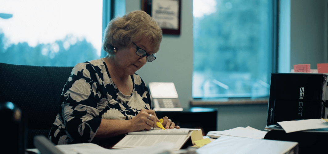 Kathy working Kathleen Wolz sitting at desk researching material and making highlights of important information