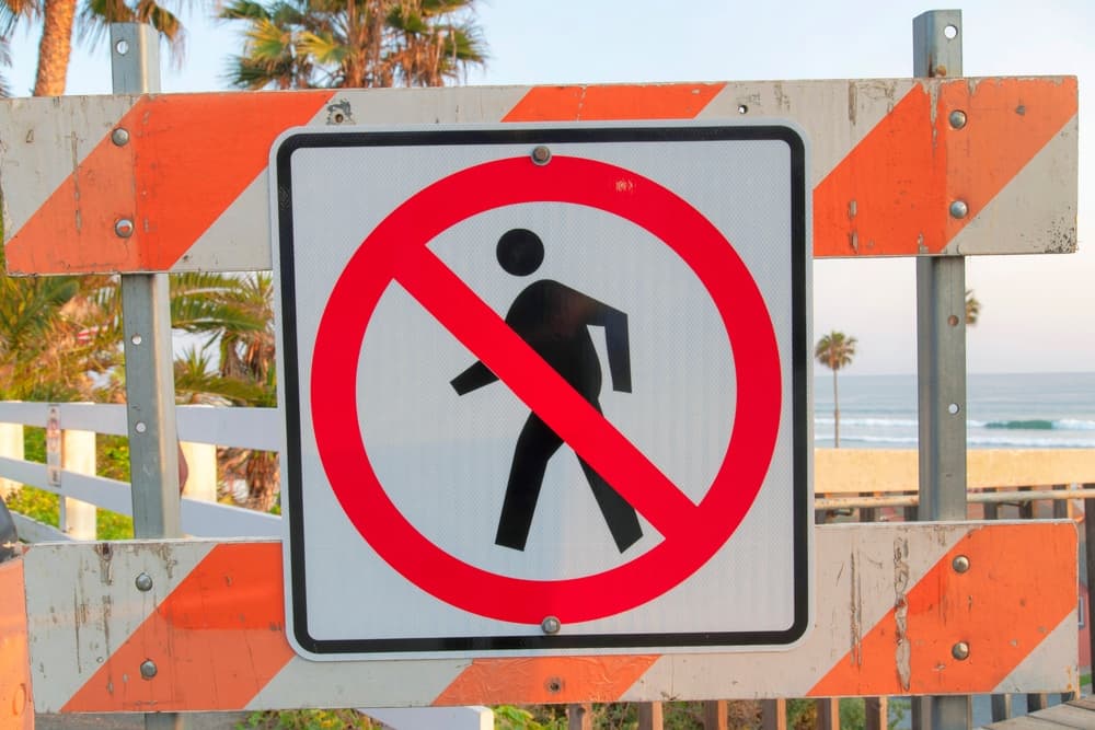 No jaywalking sign on a white and orange barricade