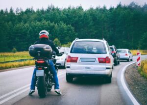 A motorcyclist passing car on the road