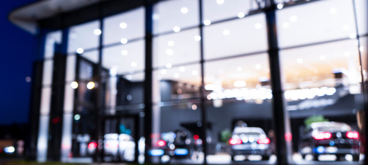 Blurred background with car dealership exterior. Abstract blurred photo of modern building motor showroom. Blur car show room office bokeh lights. Automobile retail shop