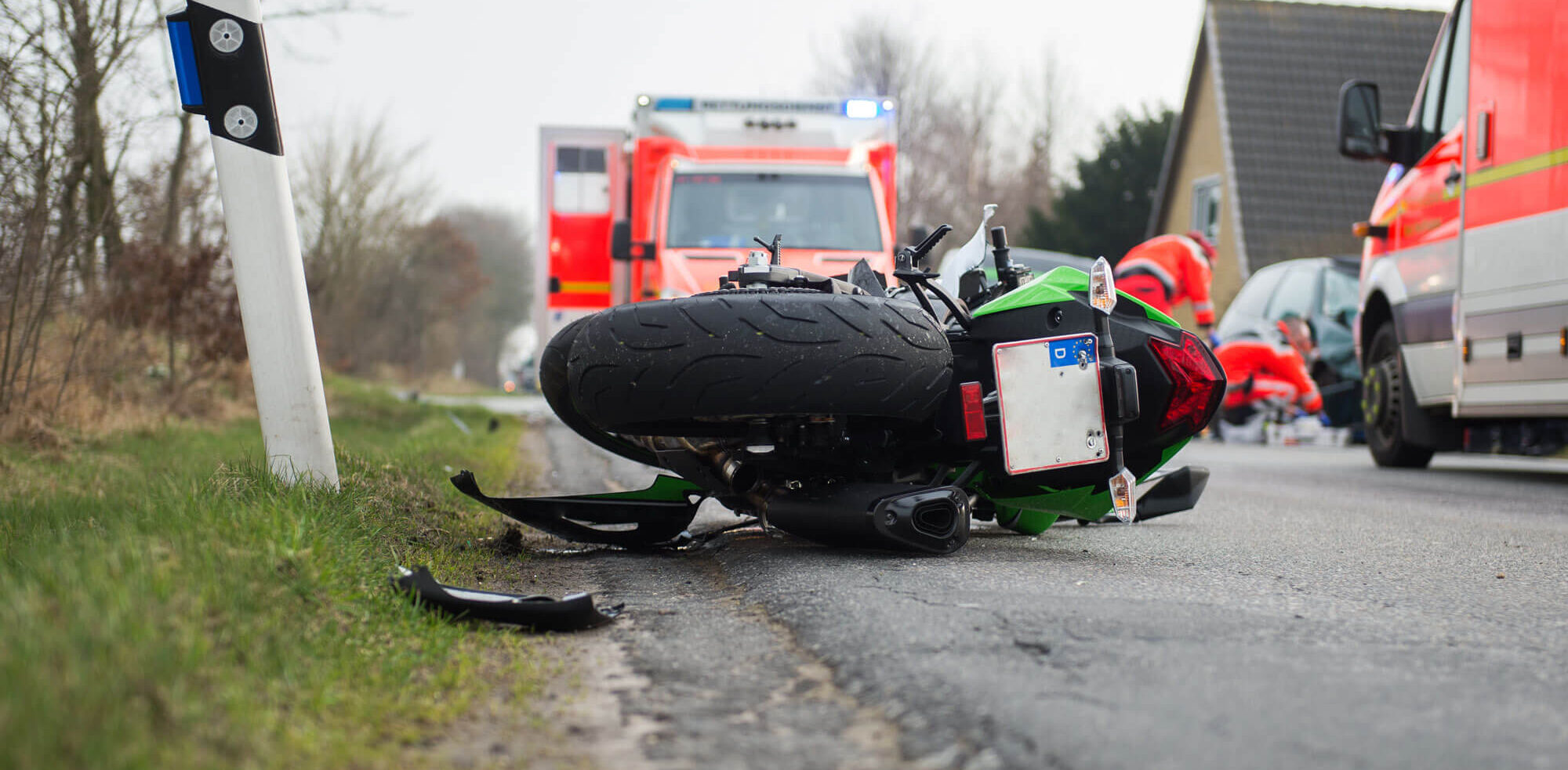 Crashed Motorcycle on the side of the road with an ambulance in the background