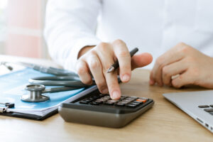 Doctors using a calculator to analyze medical reports and expenses, representing injury claim valuation.