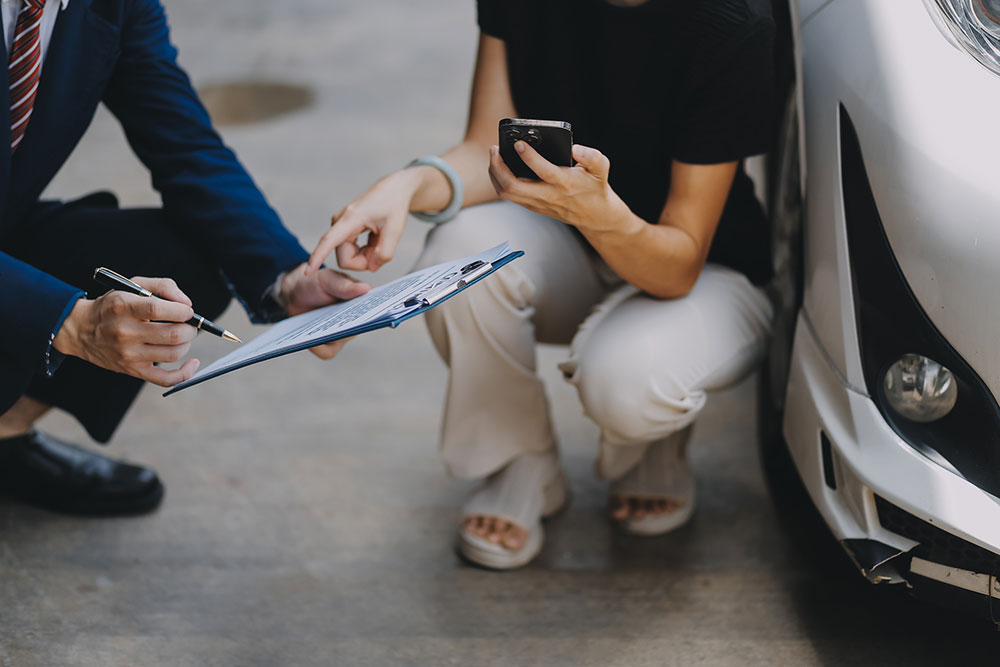 Woman reviewing car insurance policy and settlement paperwork at a desk.
