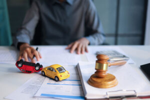 Gavel next to a small car model representing a car accident settlement or lawsuit.
