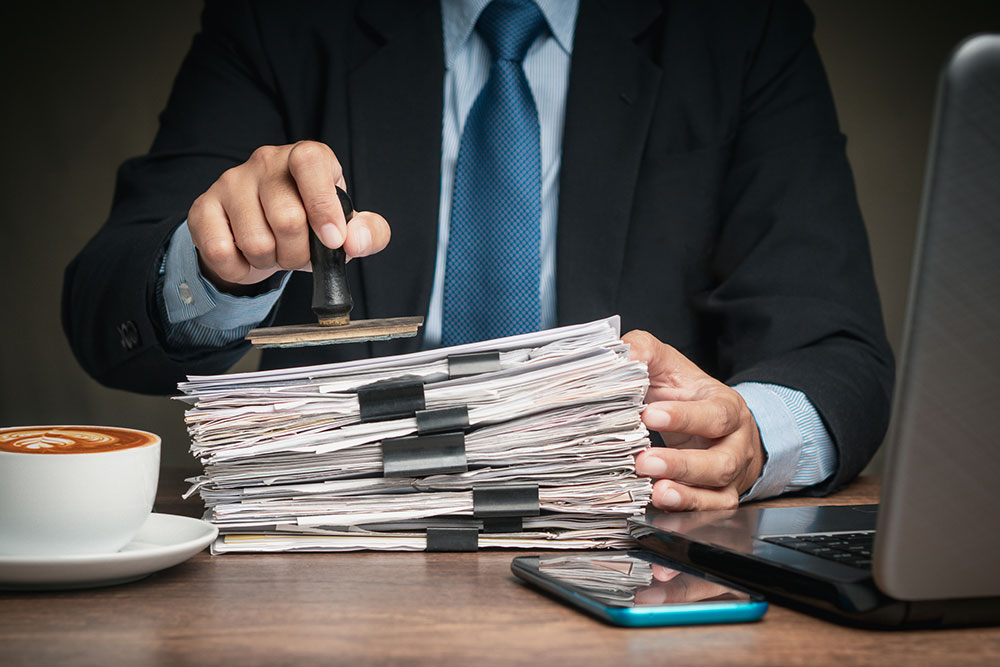 Man stamping paperwork in an office, representing filing documents and claim deadlines.