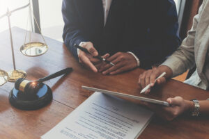 Lawyer team meeting with a client using a tablet and laptop to review a car accident claim.