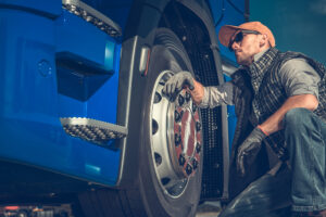Truck driver inspecting tires on a commercial vehicle, representing maintenance and safety evidence after a crash.