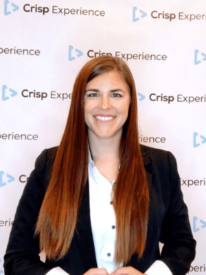 Rachael Leadbetter smiling in front of a Crisp Experience branded backdrop, wearing a black blazer and light blue blouse.