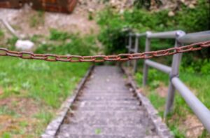 Rusty chain blocking access to deteriorating outdoor stairs representing a hazardous property condition that could support a premises liability injury claim in Missouri